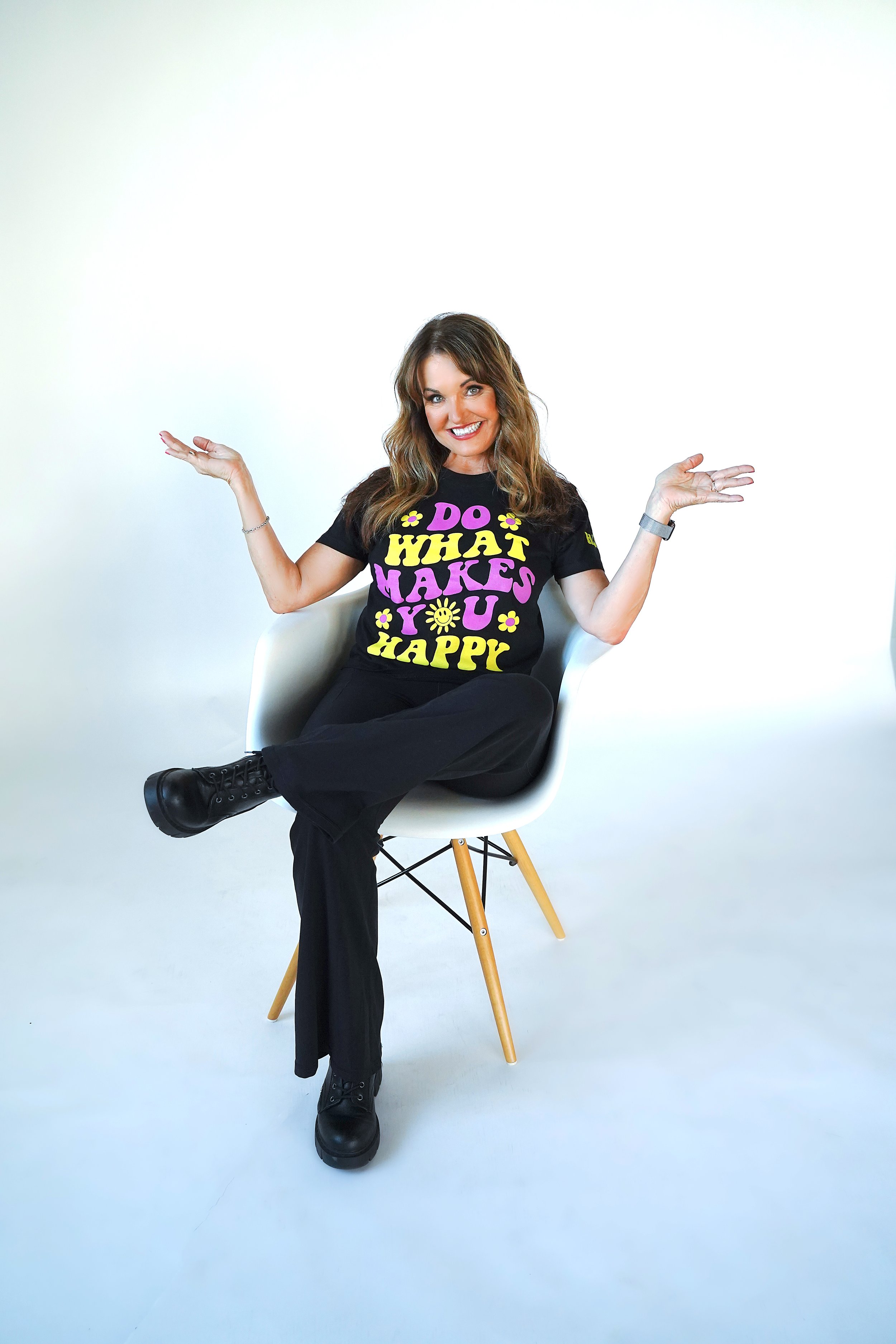 Bonnie sitting on a chair with her hands out to the side.  Her t-shirt reads Do What Makes You Happy.